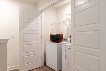 a small laundry room with white doors and a white washer and dryer at Beckington, Leland, NC